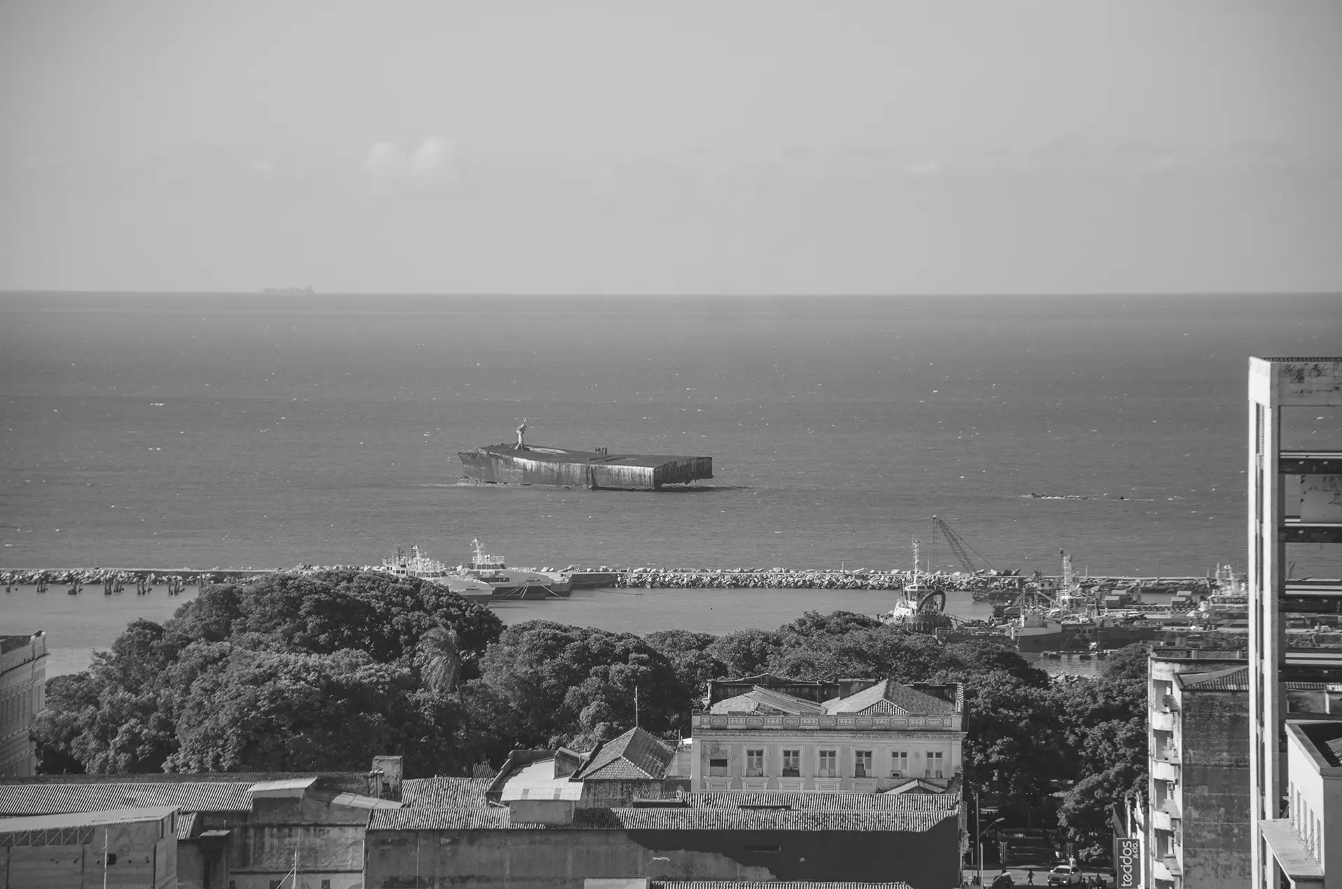 Grayscale photograph of Fortaleza's coastline where you can see the wreckage of the Mara Hope ship, which had undergone an artistic intervention