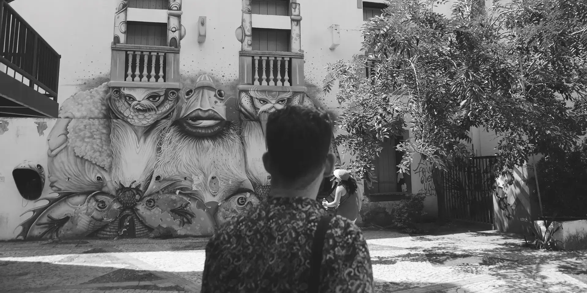 Grayscale photograph of a man from behind looking at a graffiti mural at the Dragão do Mar Cultural Center in Fortaleza