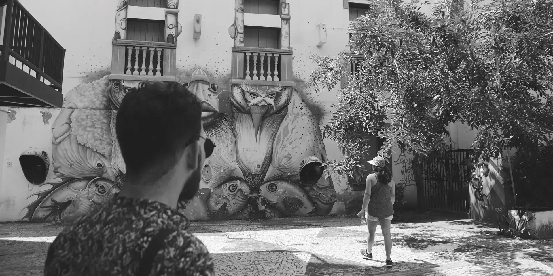 Grayscale photograph of a man from behind looking at a graffiti mural at the Dragão do Mar Cultural Center in Fortaleza