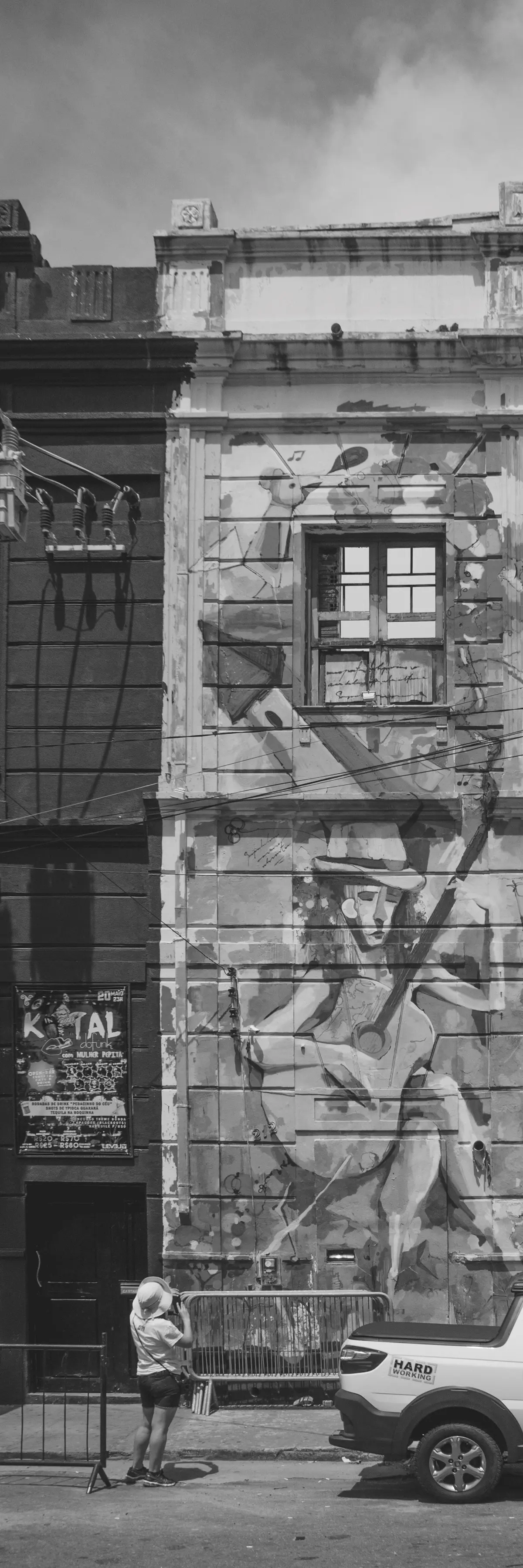 Grayscale photograph of an old building completely covered in graffiti with a woman from behind observing the building