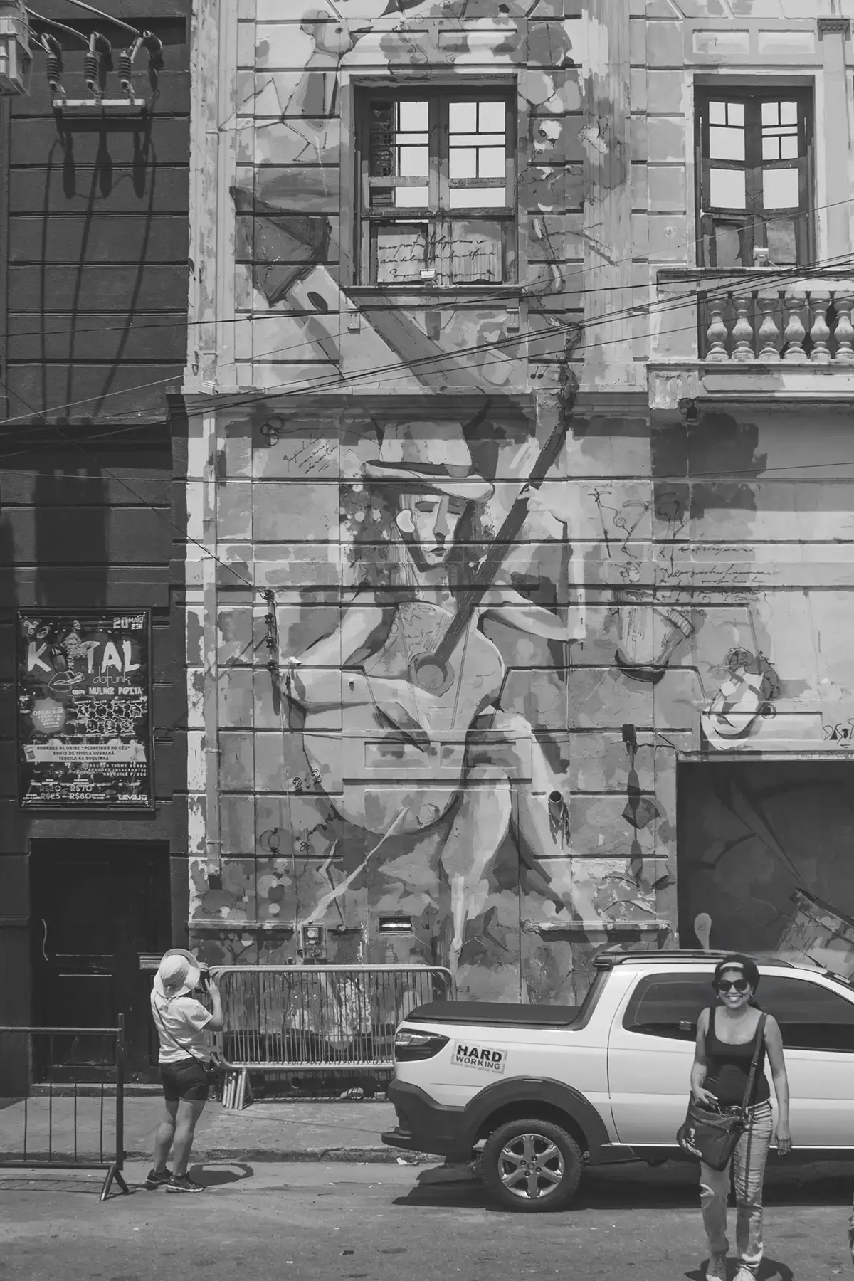 Grayscale photograph of an old building completely covered in graffiti with a woman from behind observing the building
